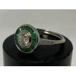 A platinum diamond and emerald ring, central stone