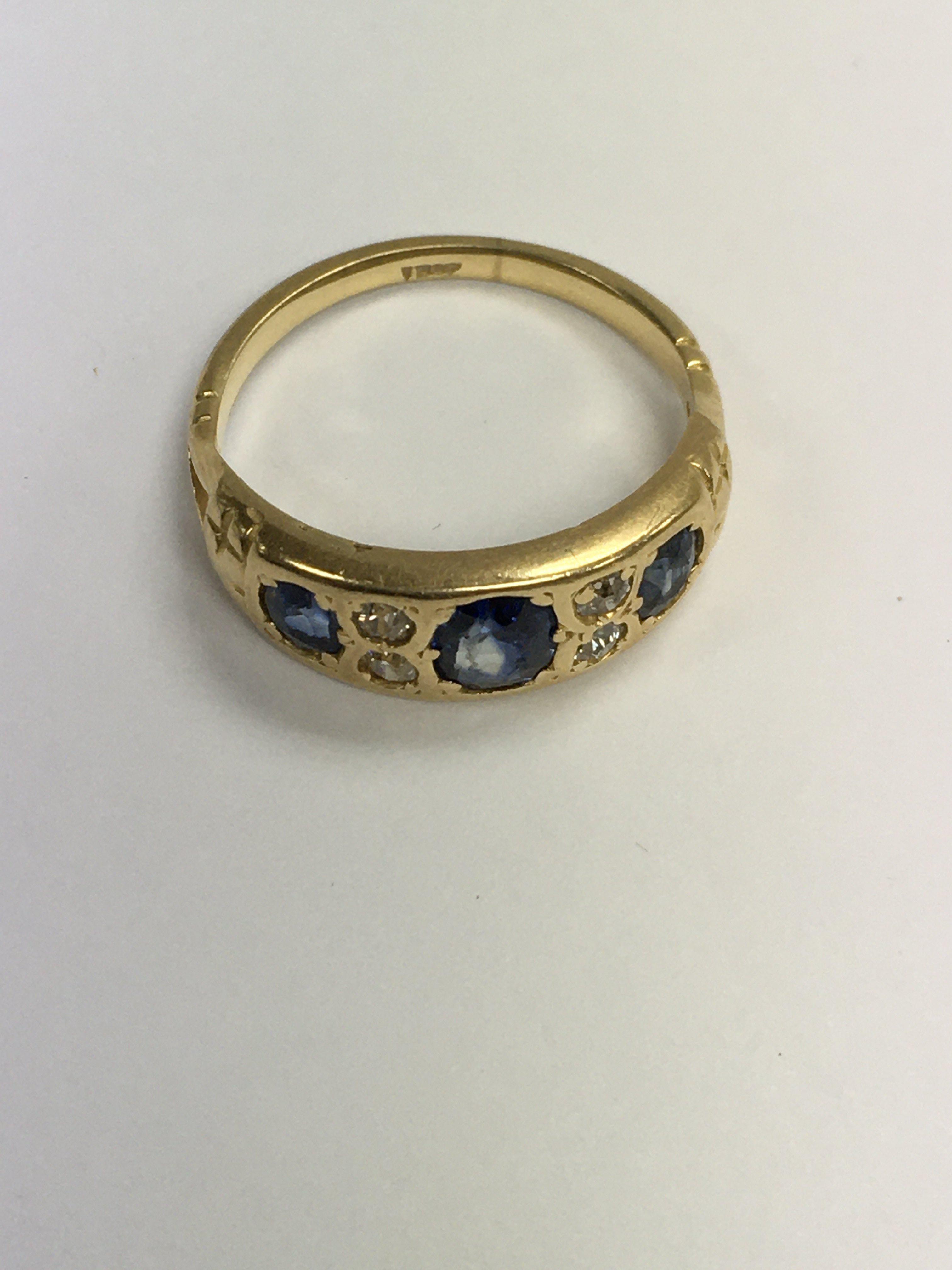 A gold ring inset with three sapphires and four di