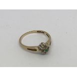 A 9ct gold ring set with an emerald and diamond cl