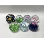 A collection of seven glass paper weights includin