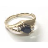 An 14 carat gold ring set with a blue sapphire flanked by two brilliant cut diamonds. Ring size N-O