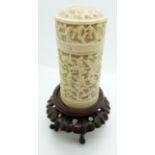 A 19thC carved Chinese ivory pot depicting court scenes, on a hardwood stand, 11cm