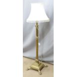 A brass standard lamp with stepped base raised on four lion pad feet, H140cm