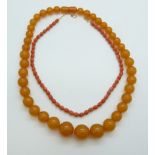 A carved coral necklace threaded on a chain and an amber style necklace