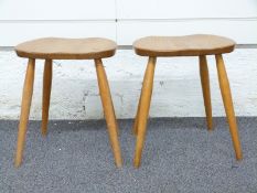 Two Ercol light elm stools with visible joints raised on four legs, 40 x 32 x 35cm