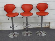 Three contemporary chrome and red upholstered bar or kitchen stools