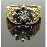 A 9ct gold ring set with a diamond and sapphires with textured shoulders, size O/P, 4.80g