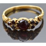 Victorian yellow metal ring set with a garnet cabochon flanked by further garnets, with pierced