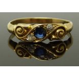 An 18ct gold ring set with a sapphire and two diamonds in a scrolling setting, size N/O, 2.31g