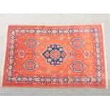 Turkoman rug with central navy blue gul and four other guls on a wine ground within a blue border,