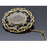 Victorian mourning brooch set with black enamel reading "In Memory Of" inside a scrolling border,
