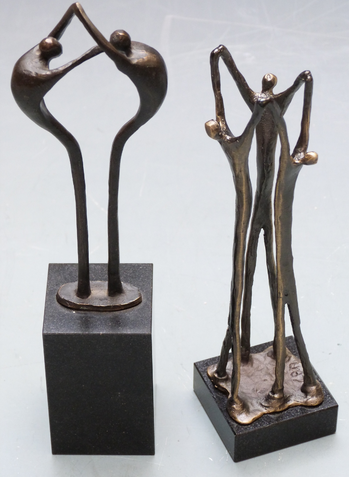 Two Artihove bronzes / bronze sculptures of people linking arms with maker's label to base, one