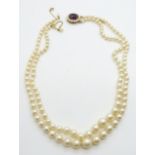 A double strand of cultured pearls with a 9ct gold clasp set with an amethyst and pearls