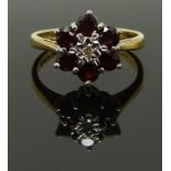 An 18ct gold ring set with a diamond surrounded by garnets, size K, 3.39g
