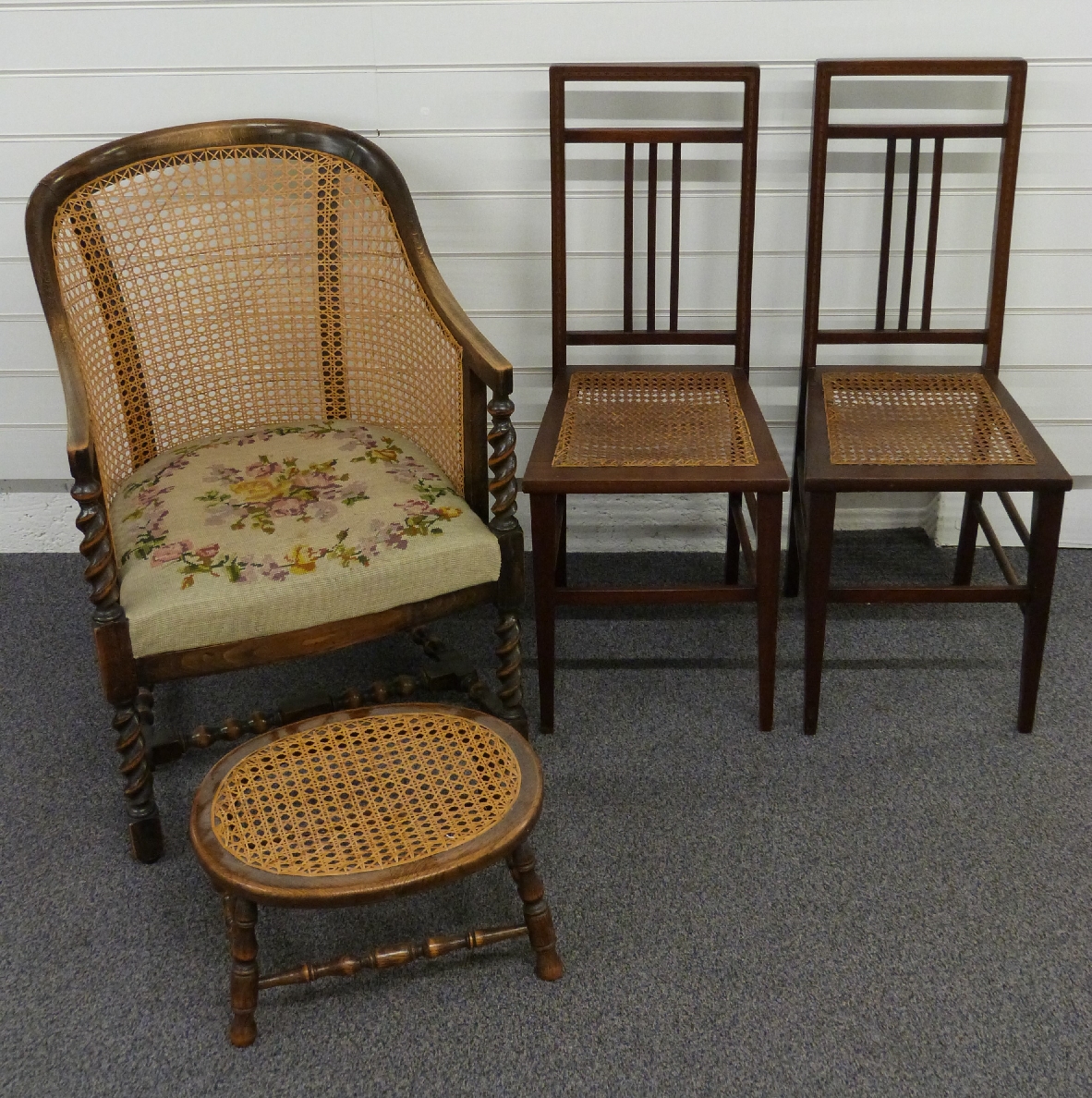 Three bergere chairs, one with tapestry upholstery, barley twist legs and a footstool
