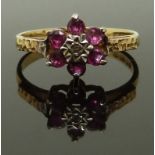A 9ct gold ring set with rubies and a diamond with textured shoulders, size N, 2.13g