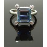 An 18ct white gold ring set with and emerald cut aquamarine and four diamonds, size N, 5.47g