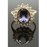 A 9ct gold ring set with an oval cut amethyst surrounded by white sapphires, size M, 3.71g