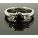 An 18ct white gold ring set with a black diamond flanked by two diamonds, each approximately 0.