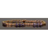 A 9ct gold tennis bracelet set with oval cut tanzanites, 19.5cm, 8.8g