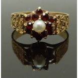 A 9ct gold ring set with a pearl surrounded by garnets with textured shoulders, size K, 2.34g