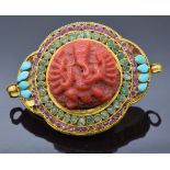 A 19thC Indian yellow metal pendant/buckle set with a carved coral section depicting Ganesh