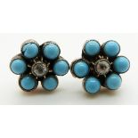 A pair of earrings set with a diamond to each surrounded by faux turquoise