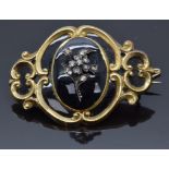 Victorian mourning brooch set with black enamel inside a scrolling border and diamonds in the form