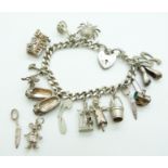 A silver charm bracelet with 11 charms including a spider, train, stork, etc