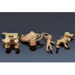 Four 9ct gold charms including a dog, astronaut, caravan, lamp, etc, 11.2g