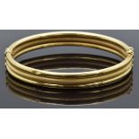 An 18ct gold bangle made up of three bands, one with a textured finish, 14.7g