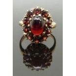 A 9ct gold ring with an opal cabochon surrounded by further garnets, size K, 3.89g