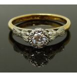 An 18ct gold ring set with a round cut diamond in a platinum setting with bow detail to the