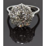 A platinum ring set with a round cut diamond of approximately 1.3ct surrounded by eight further