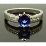 An 18ct white gold ring set with a round cut tanzanite and diamonds to the shoulders, with