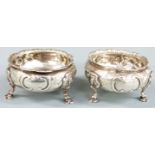 Pair of Victorian hallmarked silver salts with embossed decoration and raised on three feet,
