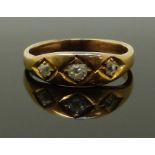 A late Victorian yellow metal ring set with three old cut diamonds, size K, 3.20g