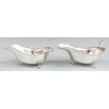 Pair of  George V hallmarked silver sauce boats with shaped edges raised on three feet, Birmingham