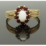 A 9ct gold ring with an opal surrounded by garnets, size M, 2.08g