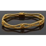 An 18ct gold bracelet made up of textured links and flower sections set with rubies, 23g