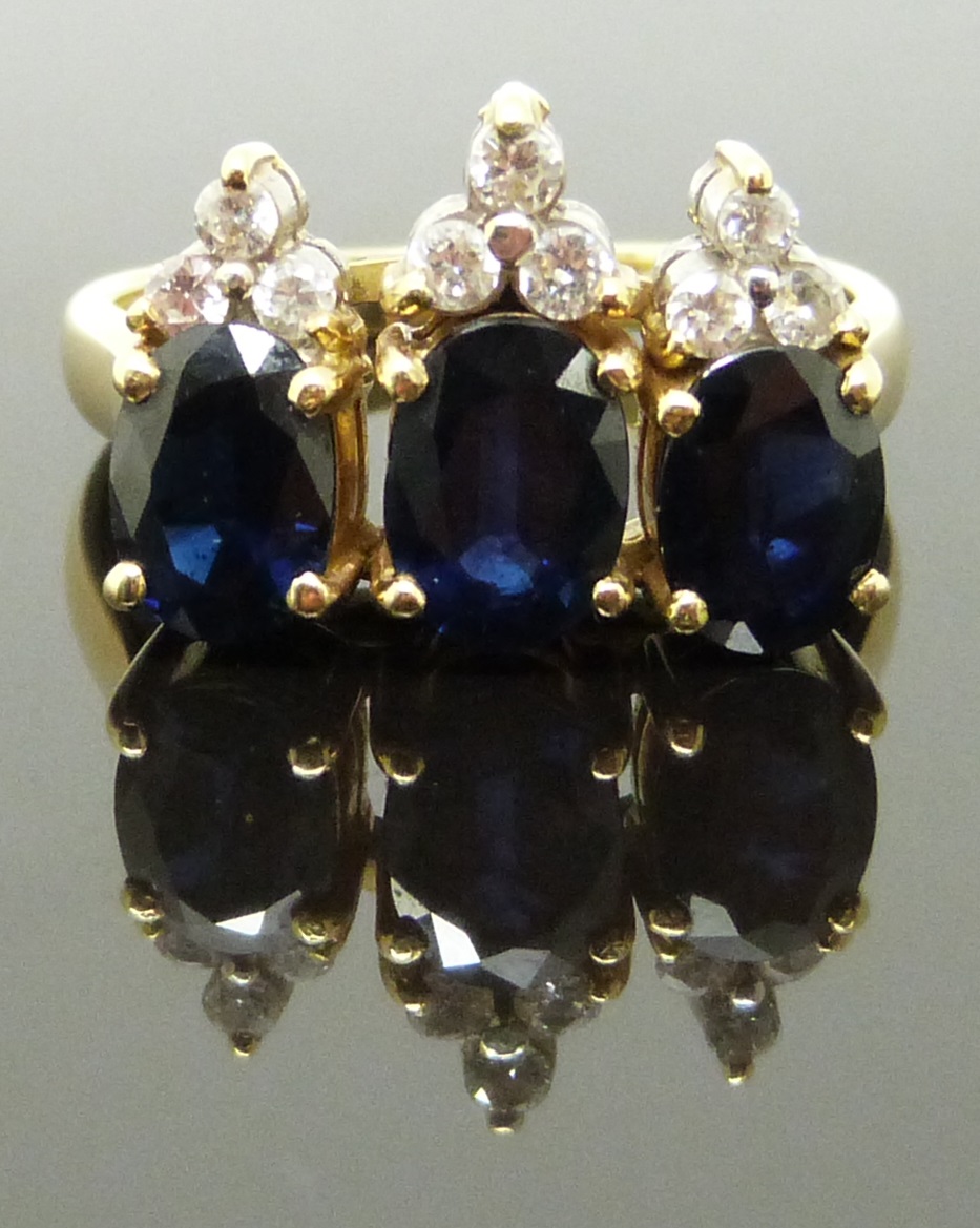 An 18ct gold ring set with three oval cut sapphires and diamonds, 6.6g, size K