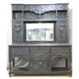 Carved oak dresser, the top being cupboards flanking a bevelled edge mirror, the base with fitted