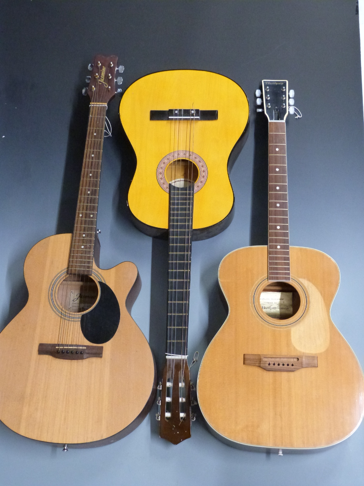 Three various acoustic guitars Jasmine S34c, in semi-rigid fitted carry case, a Harmony 6395 and a