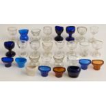 Twenty-eight glass, ceramic and other 19thC and later eye baths including Bristol blue.