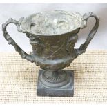 Spelter miniature twin handled vase or urn with mask and foliate decoration, on square slate or