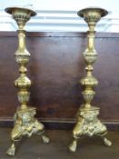 A pair of ornate brass candlesticks with lion mask and pad feed decoration, H41cm and a marble table