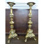 A pair of ornate brass candlesticks with lion mask and pad feed decoration, H41cm and a marble table