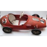 Tri-ang pressed steel pedal racing car with red body, rubber tyres and racing number 3, 118cm long.