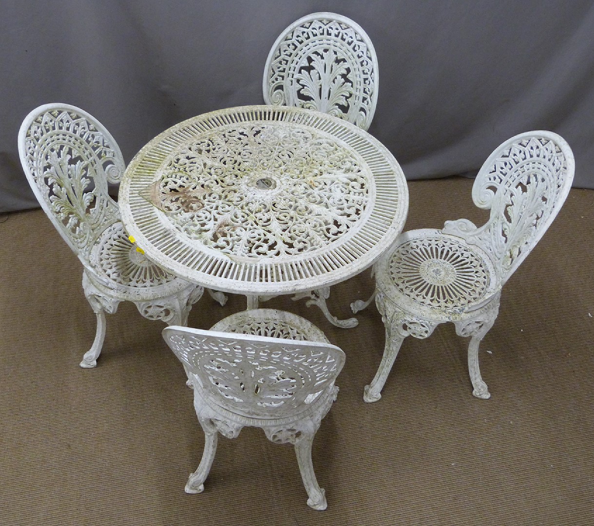 A decorative cast metal circular garden table and four chairs, diameter 80cm, height 70cm