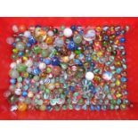 A collection of glass marbles including a large multi-coloured latticino example, largest 38mm in